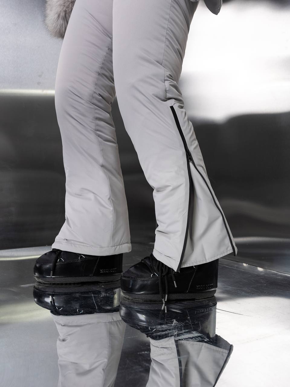 Person wearing white pants and black shoes with a reflective surface below.
