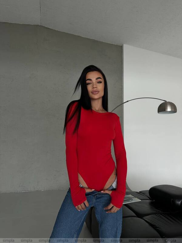 Person wearing a red sweater and blue jeans in a modern interior setting