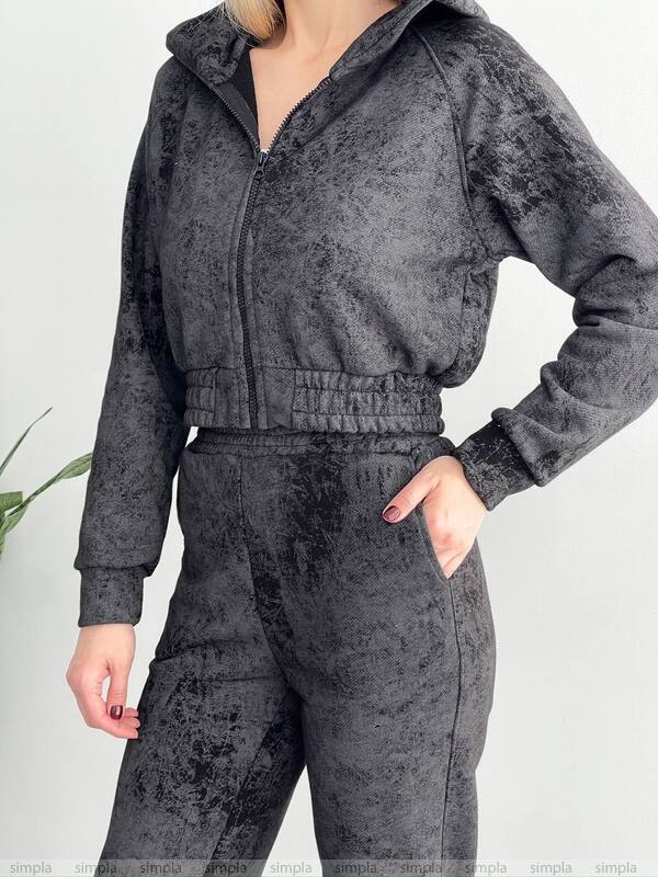 Person wearing a gray crushed velvet tracksuit on a light gray background