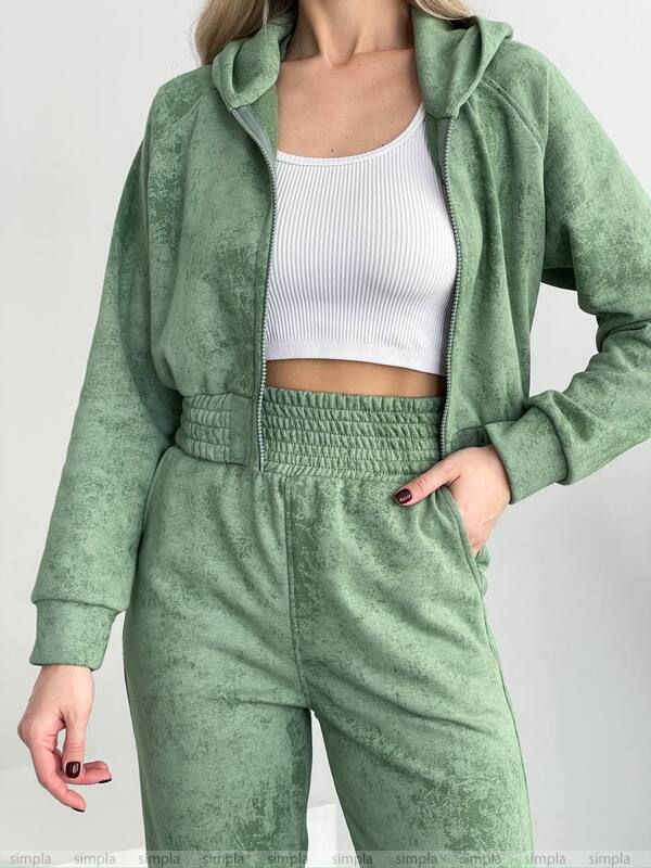 Person wearing a green tracksuit with a white top on a light gray background