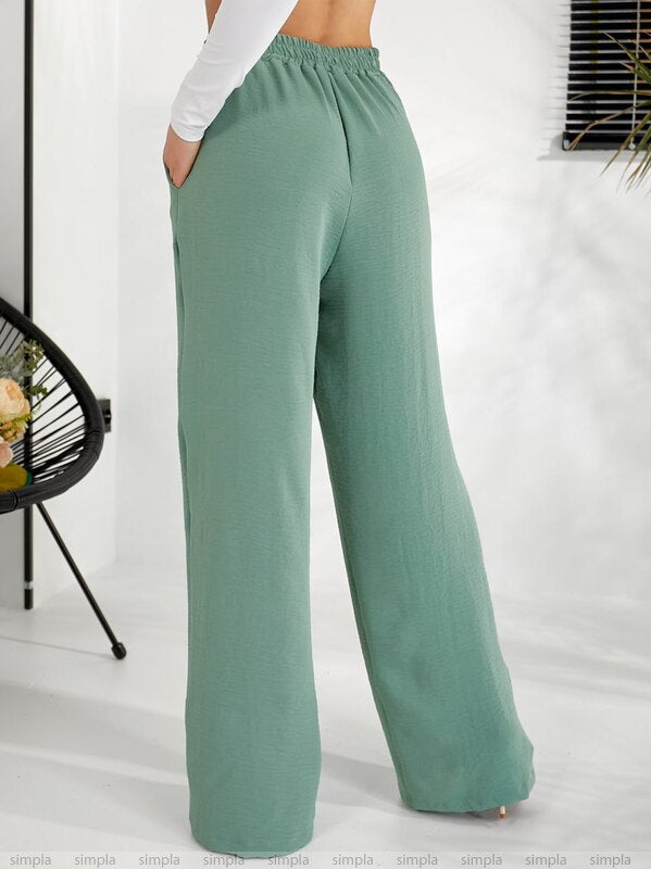 Green wide-leg pants worn by a person on a white background