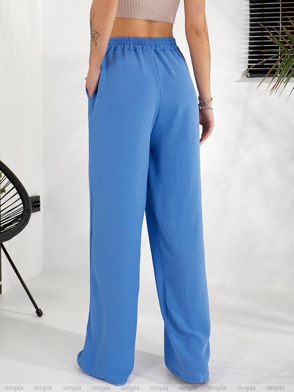 Person wearing blue wide-leg pants on a white background