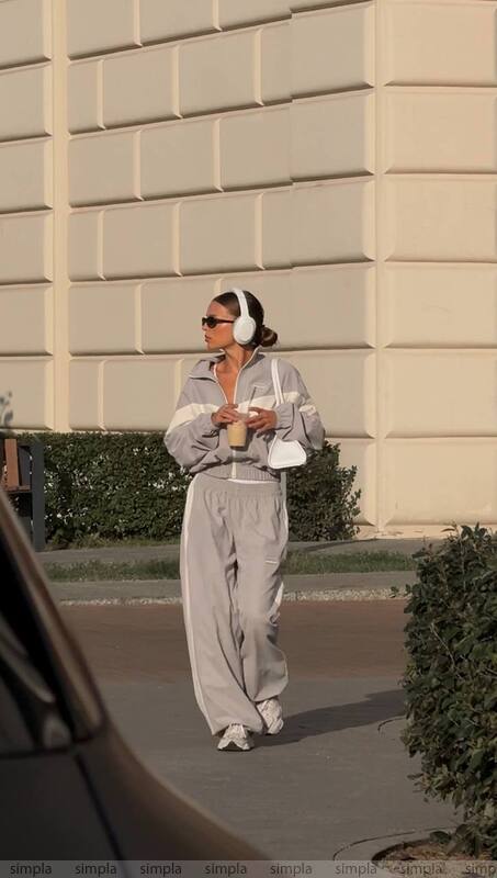 Woman in gray outfit walking outdoors with a beige building in the background