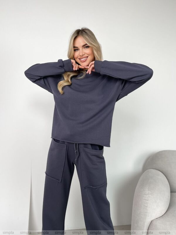 Woman wearing a dark gray outfit with a plain white background