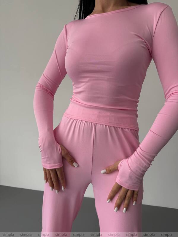 Person wearing a pink long-sleeve top and pants set against a neutral background