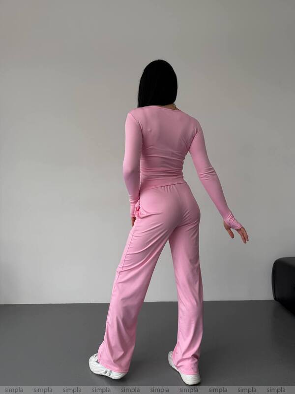 Person wearing a pink tracksuit standing against a plain background