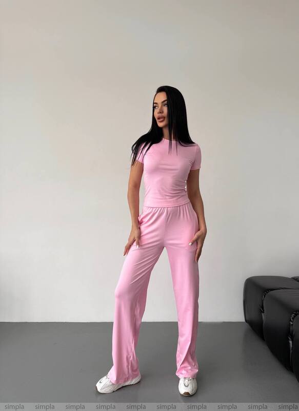 Woman wearing a pink outfit standing against a plain background