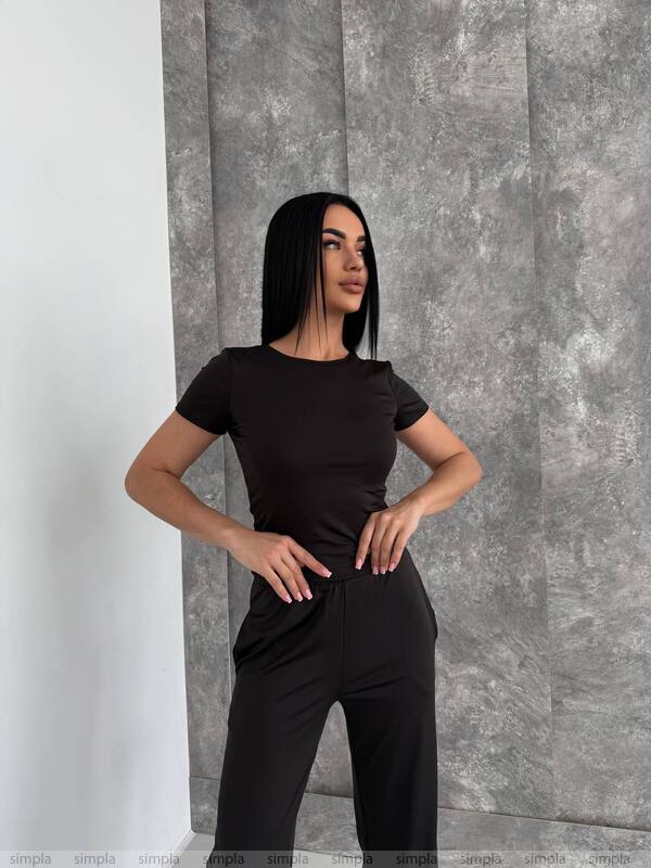 Woman wearing a black outfit against a gray textured wall