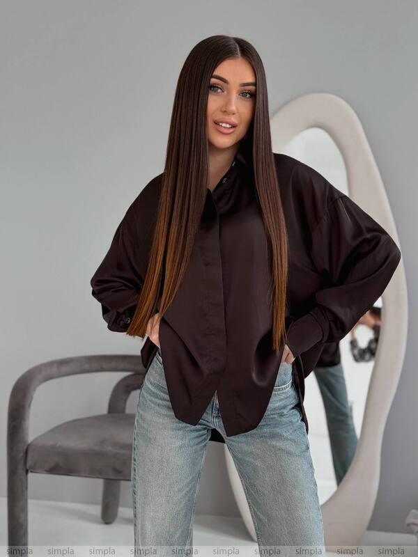 Woman wearing a black oversized shirt and light blue jeans against a gray background