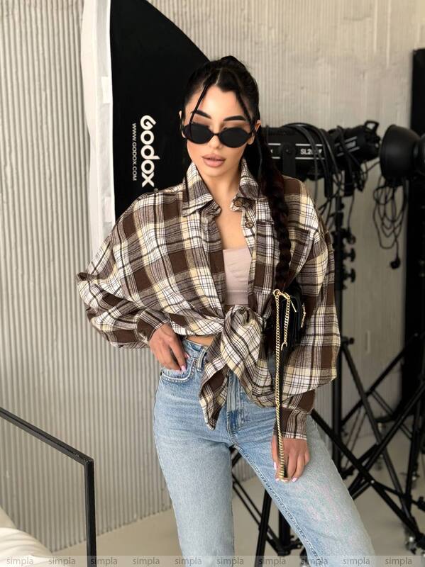 Person wearing a plaid shirt and jeans in front of photography equipment