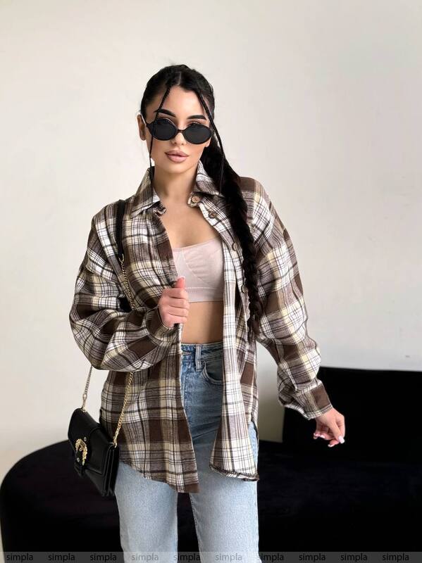 Woman wearing a plaid shirt, jeans, and sunglasses against a plain background