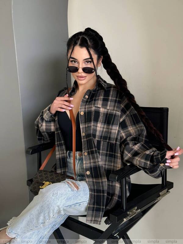 Woman wearing a plaid shirt and sunglasses, sitting on a chair.