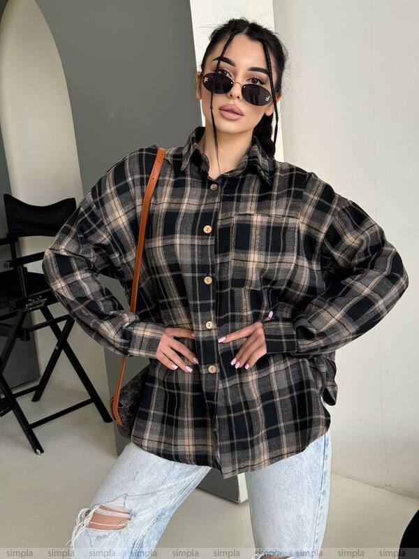 Woman wearing a plaid shirt and sunglasses indoors.