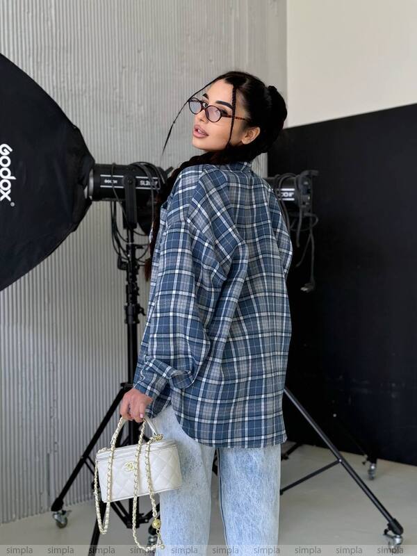 Person wearing a blue plaid shirt in a photography studio setting