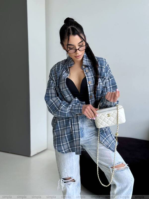 Person wearing a plaid shirt, ripped jeans, and holding a white handbag with a chain strap.