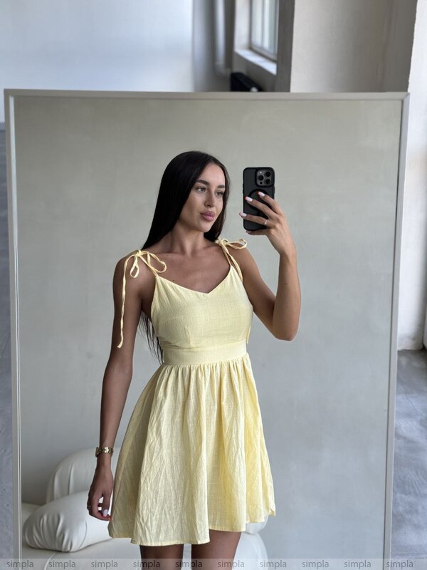 Woman taking a mirror selfie wearing a yellow dress.