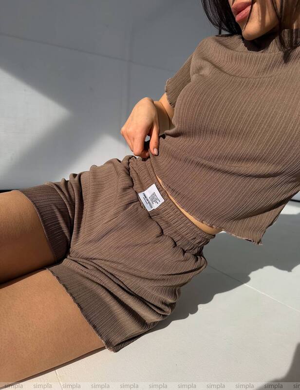 Close-up of a person wearing a brown ribbed sweater with a visible brand label.