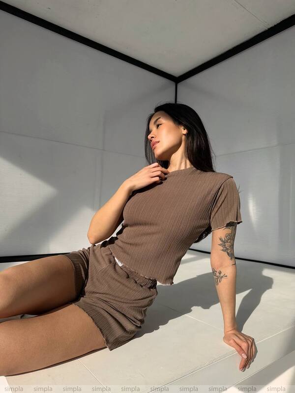 Woman in a brown outfit sitting on a white floor with a minimalistic background