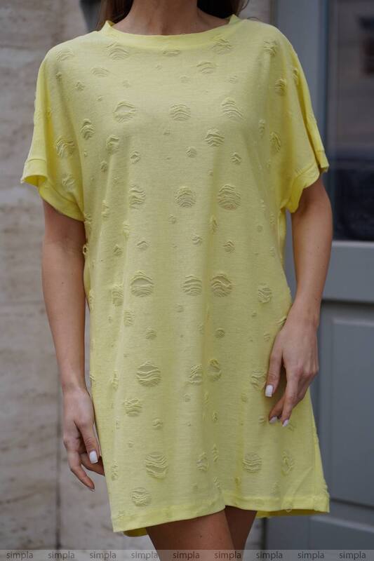 Yellow dress with textured pattern worn by a person, standing against a neutral background.