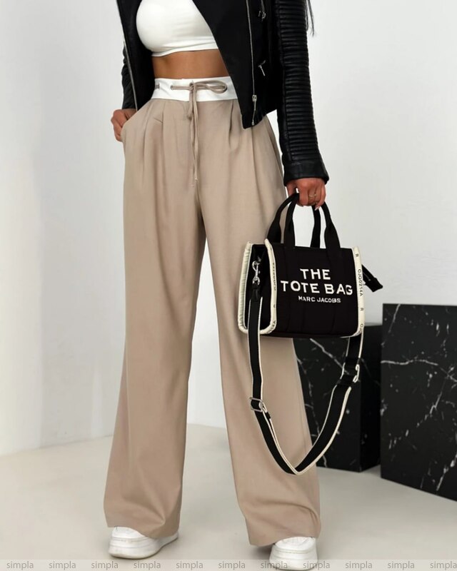 Person wearing beige pants and a black and white handbag with 'Marc Jacobs' branding.