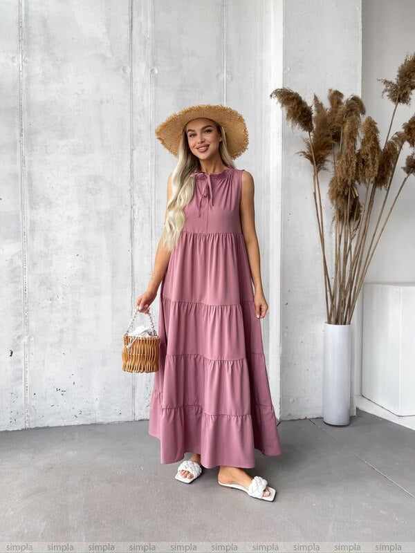 Woman in a pink dress standing in a room with a white wall and decorative elements.