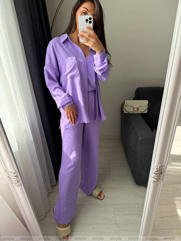 Woman taking a mirror selfie wearing a purple outfit in a room.
