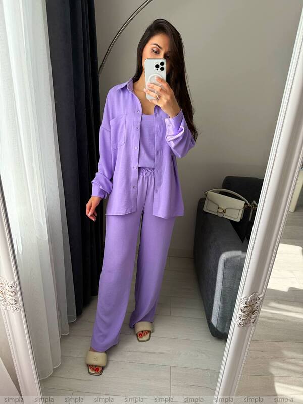 Woman wearing a purple outfit taking a mirror selfie.