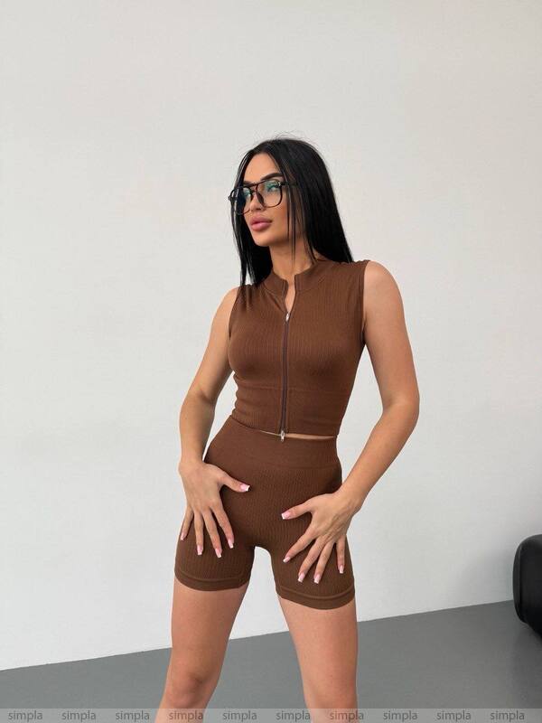 Woman wearing a brown sleeveless top and shorts set against a plain background