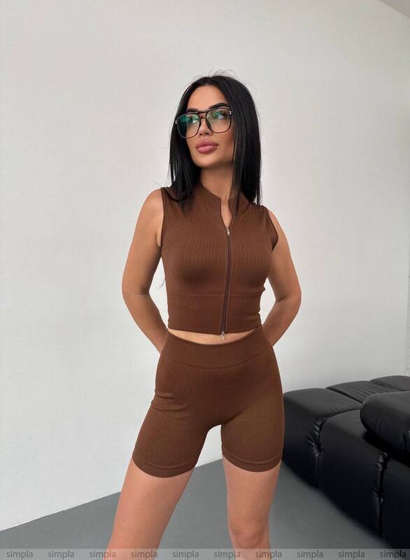 Woman wearing a brown outfit with a black sofa in the background