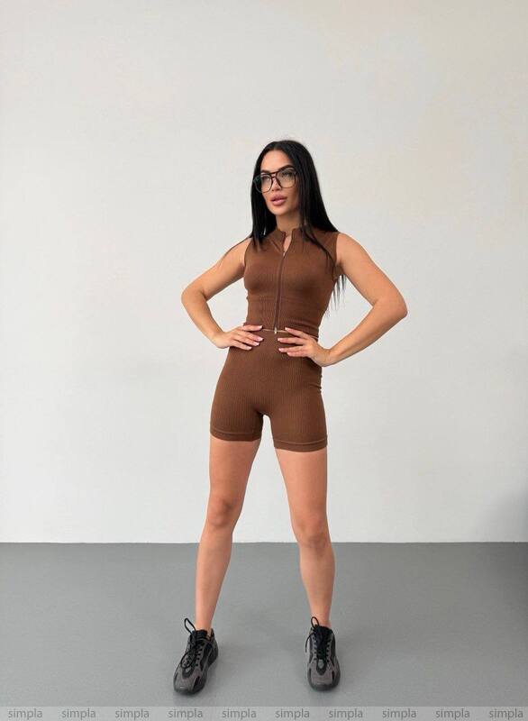 Woman wearing a brown bodysuit against a plain background