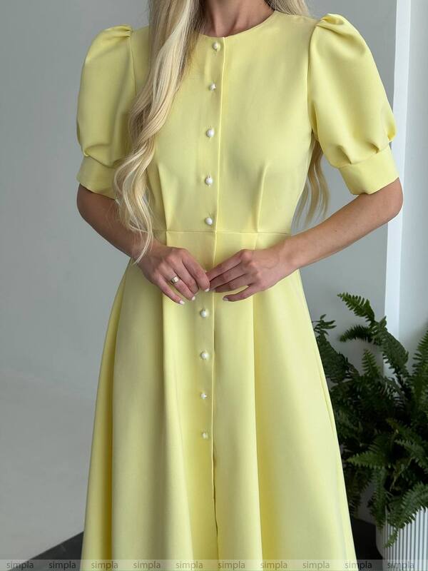 Yellow dress with puff sleeves and buttons on a plain background