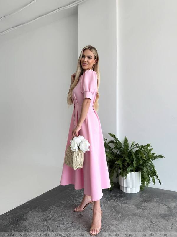 Woman in a pink dress holding flowers in a minimalistic setting