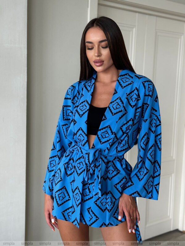 Woman wearing a blue patterned outfit standing against a neutral background