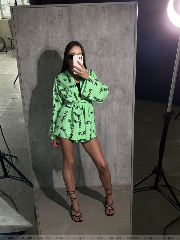 Person wearing a green outfit with black text pattern in front of a mirror.