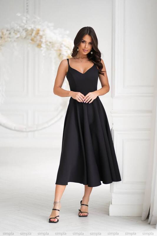 Woman wearing a black dress against a white wall