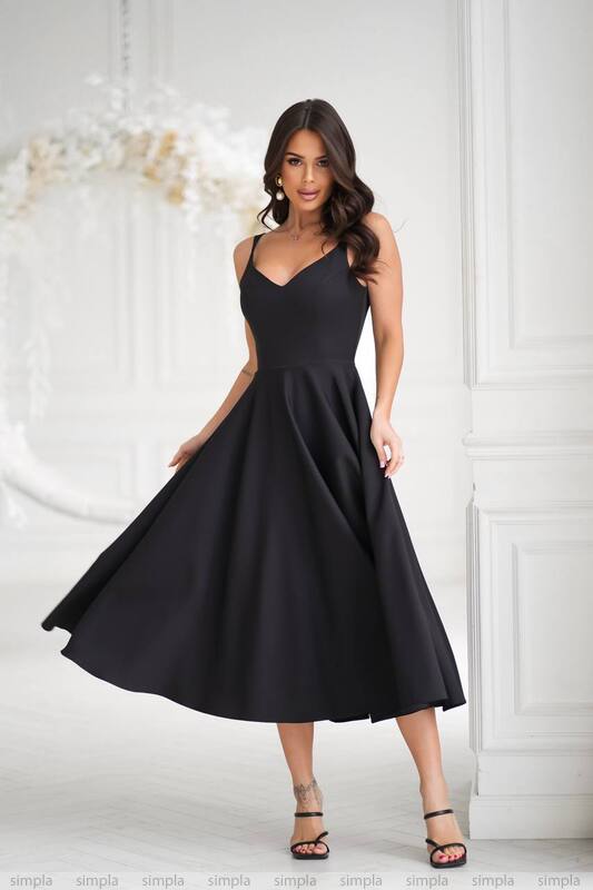Woman wearing a black dress against a white wall