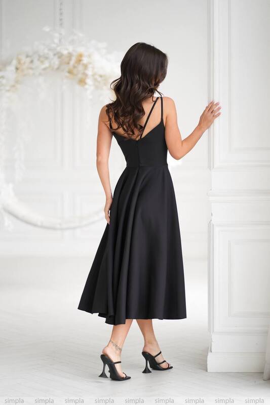 Woman wearing a black dress against a white wall