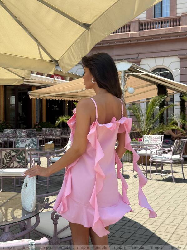 Woman in a pink dress standing outdoors under an umbrella