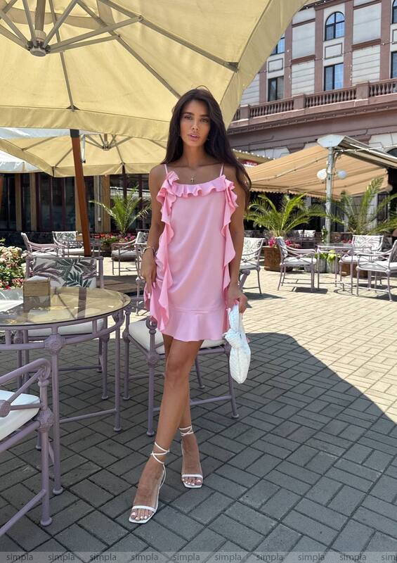 Woman in a pink dress standing under an umbrella in an outdoor setting