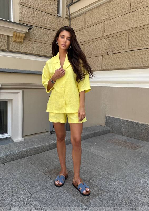 Woman in a yellow outfit standing on a street with a building in the background