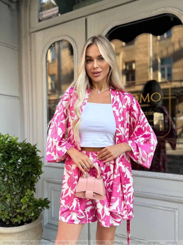 Woman wearing a pink and white outfit with a matching kimono-style jacket in front of a store.