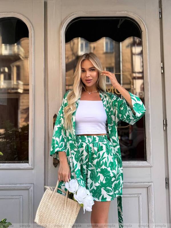 Woman wearing a green leaf-patterned kimono standing in front of a door.