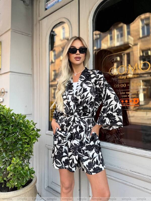 Woman in a black and white floral dress standing in front of a store entrance.