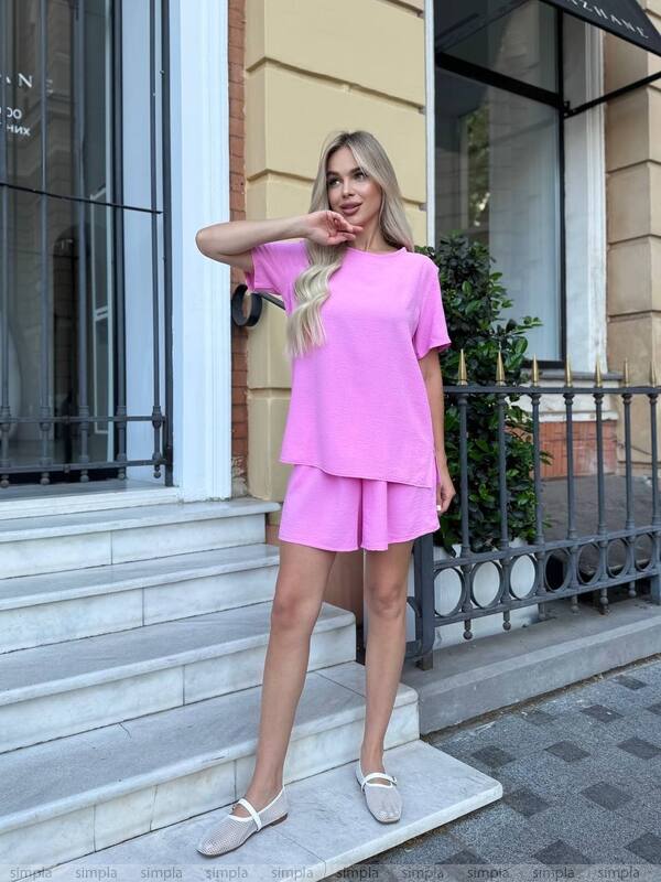 Woman in a pink outfit standing on steps outside a building