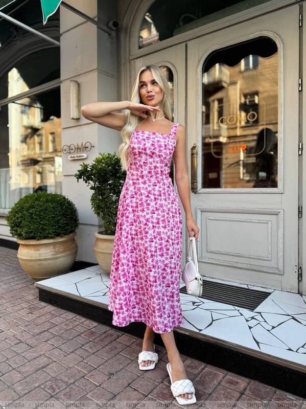 Woman in a pink floral dress standing on a city street.