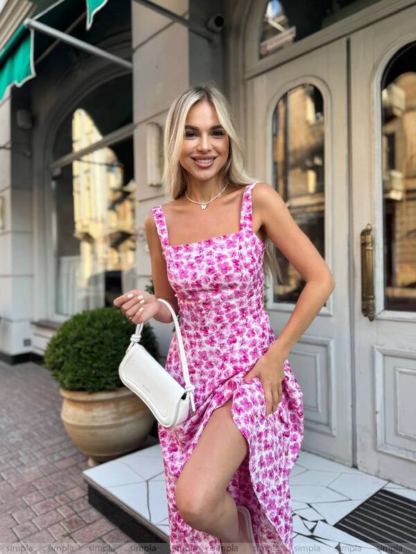 Woman in a pink floral dress standing outside a building