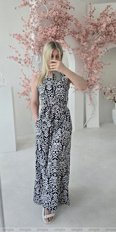 Woman wearing a black and white patterned dress standing in front of pink floral decorations.