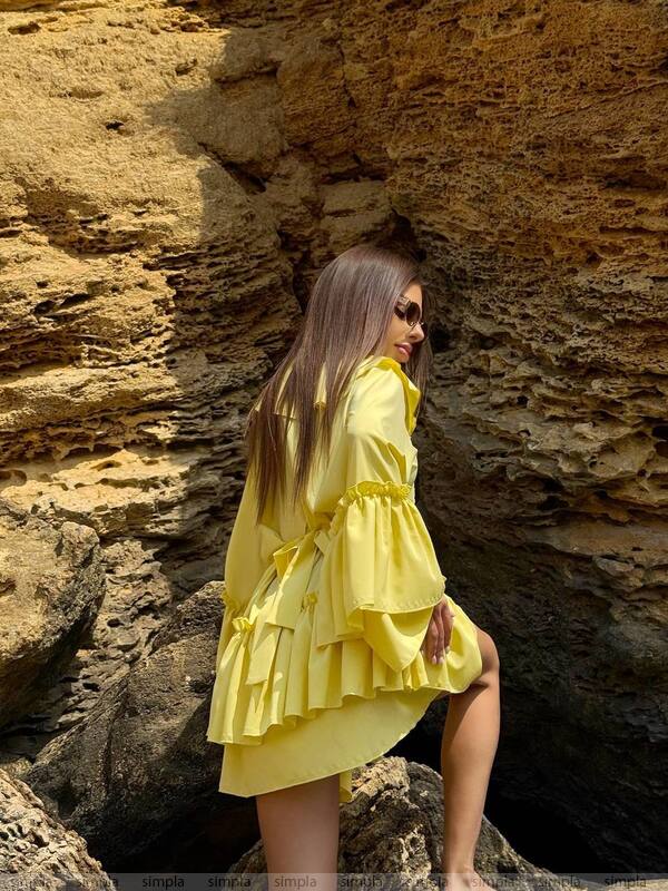 Woman in a yellow dress standing on rocky terrain
