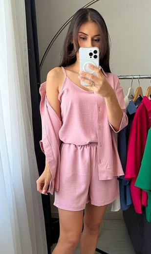 Person wearing a pink outfit taking a mirror selfie in a clothing store.