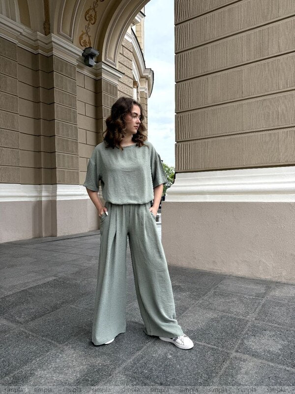 Woman in a green outfit standing in front of a classical building.